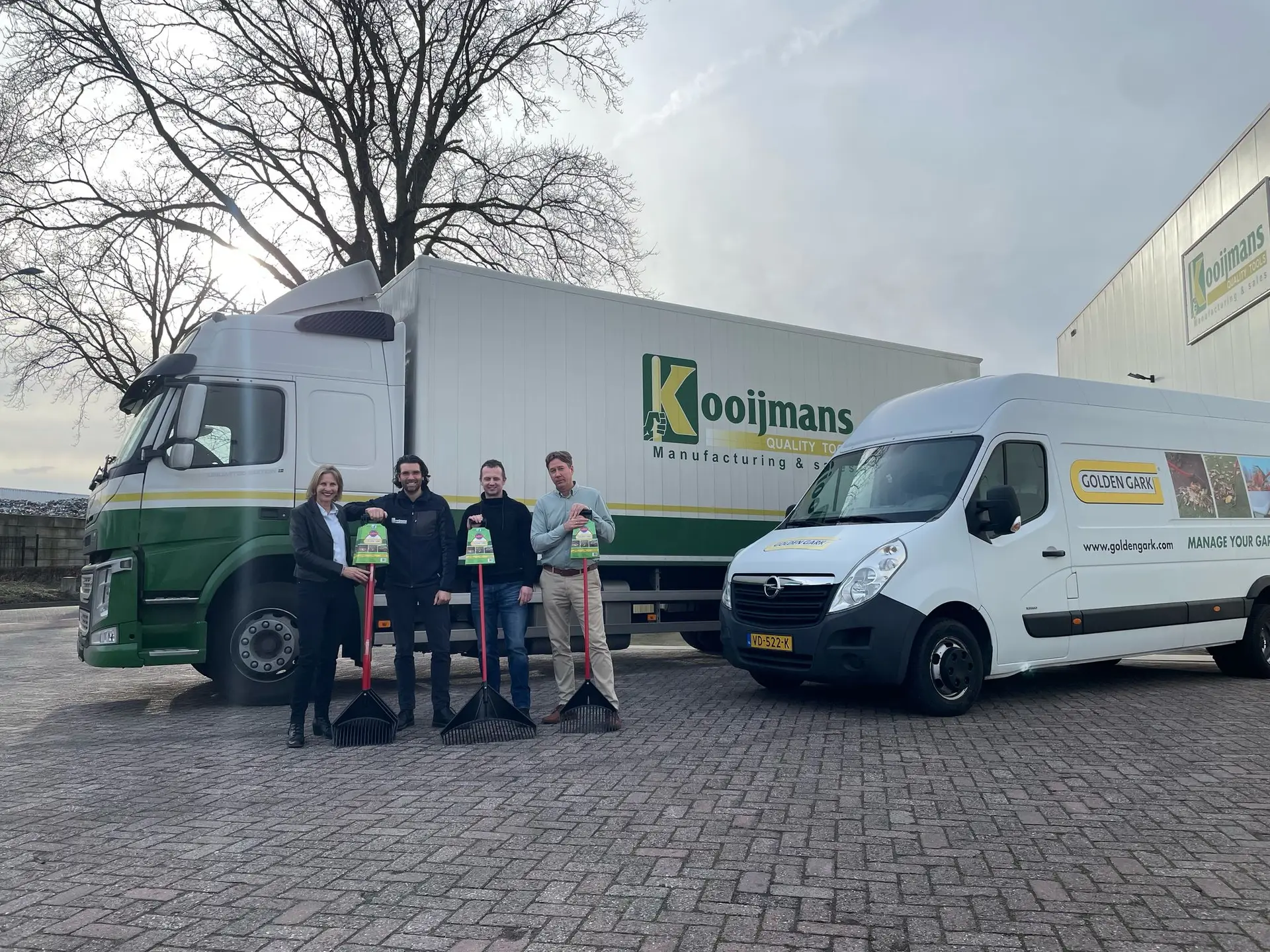 Team members of Golden Gark and Kooijmans pose in front of trucks with Golden Gark garden tools during the launch of their collaboration